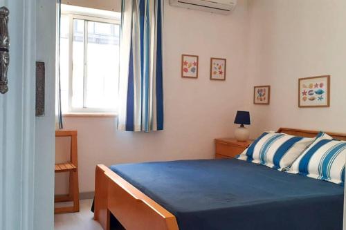 波尔蒂芒Cozy beach front apartment的一间卧室配有一张带蓝色床单的床和一扇窗户。