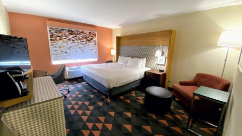 斯帕坦堡Holiday Inn Spartanburg Northwest的配有一张床和一把椅子的酒店客房