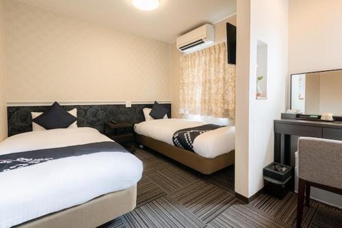 TaruiHotel Sunmarine的酒店客房配有两张床和一张书桌