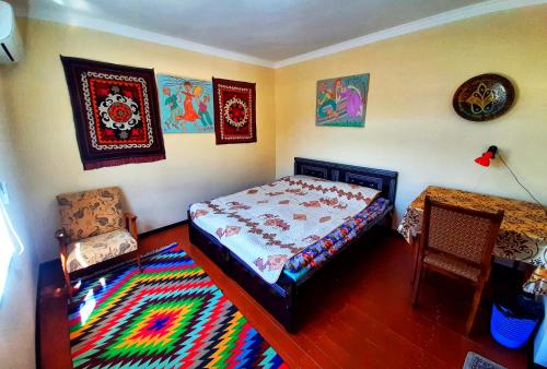 布哈拉Art Guest House USTO的一间卧室配有一张床、一把椅子和地毯
