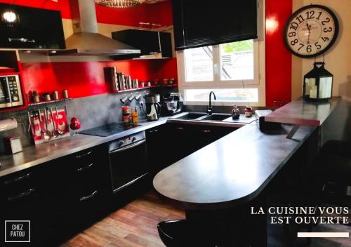 拉瓦勒Chez Patou的厨房设有红色的墙壁和墙上的大时钟