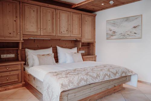 莱赫阿尔贝格Das Verwall - finest serviced apartments的一间卧室配有一张带木制橱柜的大床