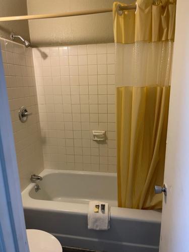 约翰逊城Bravo Inn的带浴缸和黄色淋浴帘的浴室