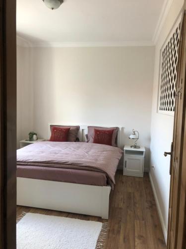 陶波尔曹Apartman Tapolca Belváros的白色卧室配有红色枕头的床
