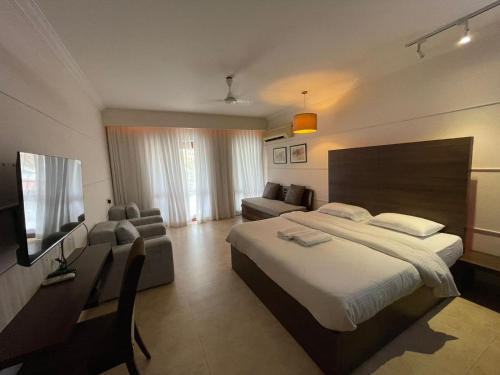 巴加Casa Legend Villa & Apartments Arpora - Baga - Goa的一间卧室配有一张床、一张沙发和一台电视