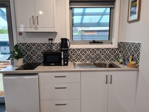 温耶德Kadi House - Unit 1的厨房配有白色橱柜、水槽和窗户。