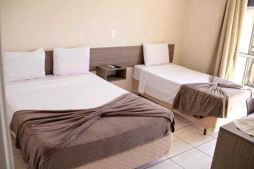 瓜拉普阿瓦Royal Trip Hotel的酒店客房设有两张床和窗户。