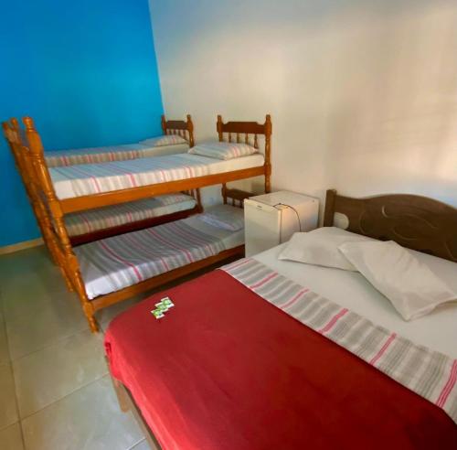 卡拉瓜塔图巴Pousada Cauna的一间设有三张床和红色毯子的房间