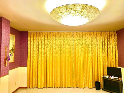 犬山市犬山モダンルーム的一间设有黄色窗帘和吊灯的房间
