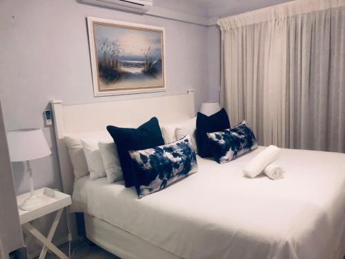 乌姆德洛蒂Sands Beach Breaks Umdloti Beach View的一间卧室配有一张带蓝色和白色枕头的床