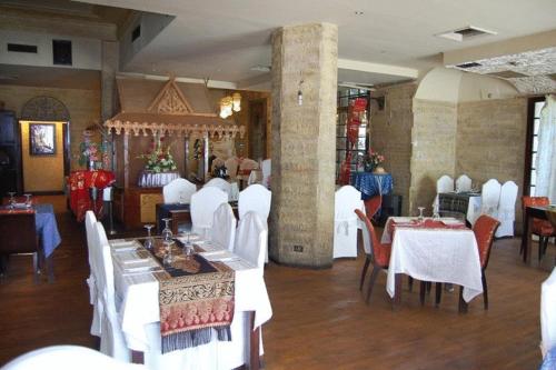开罗尼罗扎马雷克酒店的用餐室配有白色的桌子和白色的椅子