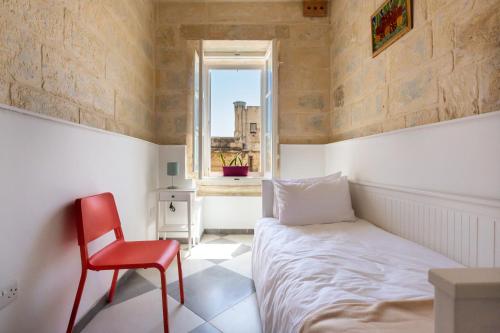 瓦莱塔Valletta Collection - St Pauls Apartment的一间卧室配有一张床和一张红色椅子