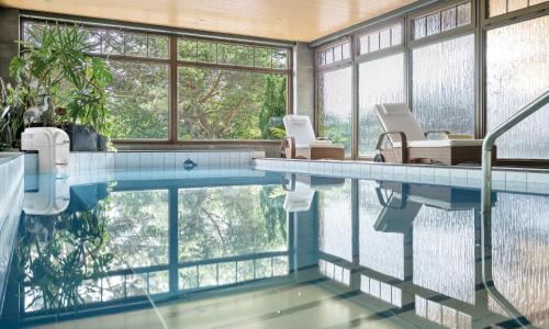 奥伯霍夫奥伯霍夫斯驰洛斯伯格酒店的带2把椅子的游泳池,位于带窗户的房间内