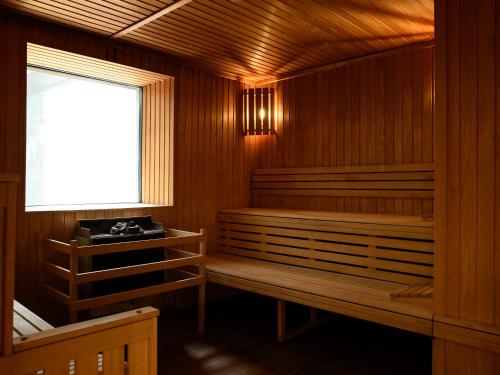 岩尼维利昂内维尔金色郁金香酒店的一间设有两个木制长椅和窗户的桑拿浴室