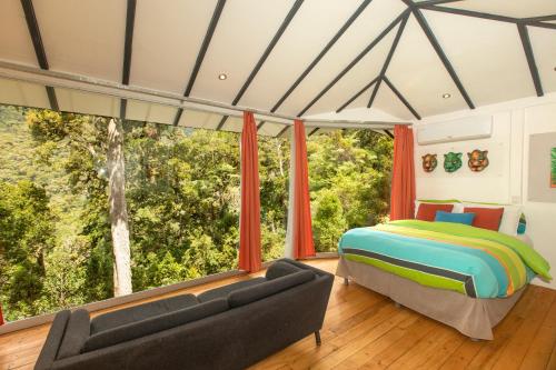 圣赫拉多德多塔旦提卡云中森林旅社的卧室配有一张床,窗户前配有一张沙发