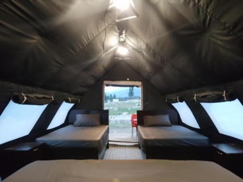 TālKumrat Glamping Resorts的带窗户的帐篷内带两张床的房间