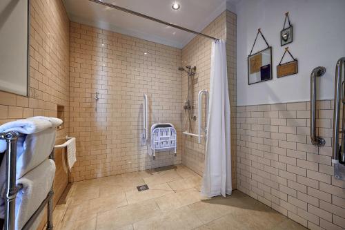 巴斯船库酒店的带淋浴的浴室和瓷砖墙壁。