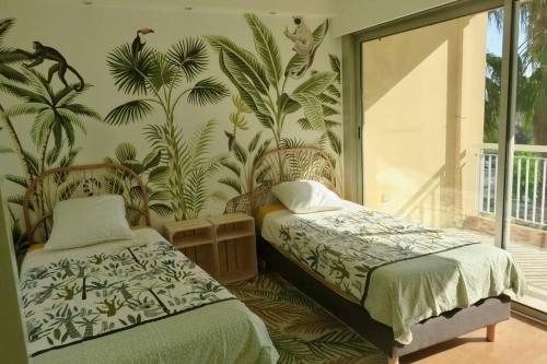曼德琉-拉纳普勒Appartement lumineux 6 places avec vue sur Marina的一间卧室设有两张床,并拥有棕榈树壁画。