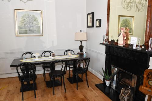 穆林加尔Railway House Guest House的一间带桌椅和壁炉的用餐室