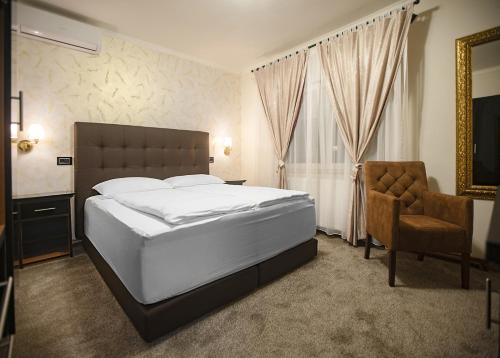 巴尼亚卢卡ŽAD Apartments and Rooms的一间卧室配有一张大床和一把椅子