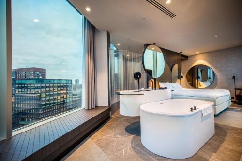 阿姆斯特丹Van der Valk Hotel Amsterdam Zuidas -Rai的带浴缸的浴室和大窗户