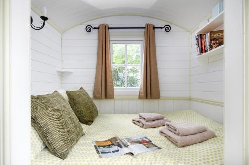 凯尼尔沃思Romantic Shepherds Hut, Kenilworth的带毛巾和窗户的床的客房