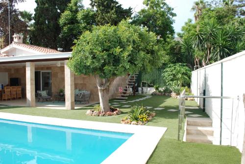 马拉加CASA VACACIONAL MÁLAGA 14 Chalet的一座带游泳池和树的院子,毗邻一座房子