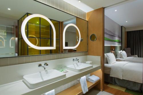 天津天津融侨套房假日酒店的一间带两个水槽和一张床的酒店浴室