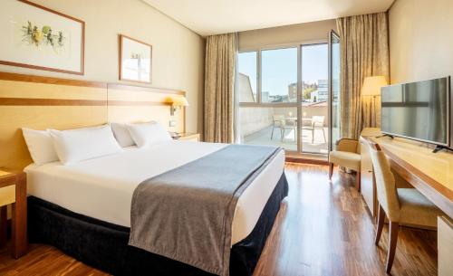 马德里伊鲁尼阿尔卡拉北部酒店的酒店客房配有一张床、一张书桌和一台电视。