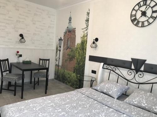 普沃茨克Płock by day的一间卧室配有一张床、一张桌子和闹钟
