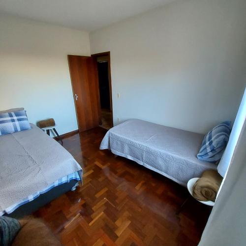 迪维诺波利斯Apartamento Aconchegante的一间卧室设有两张床,铺有木地板