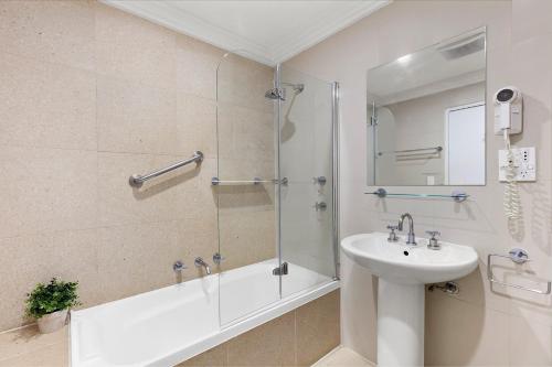凯阿玛Harbourside Studio Apartment的带淋浴、盥洗盆和浴缸的浴室