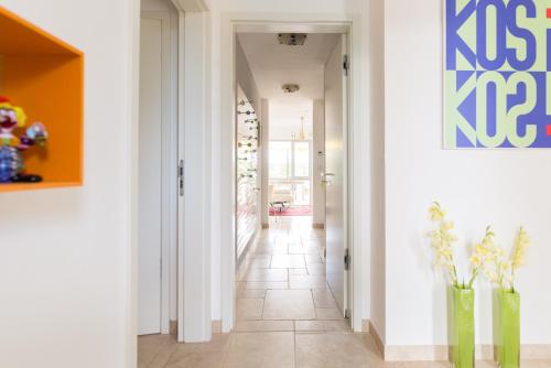 Gerbrunn伊丘之家公寓的走廊设有白色墙壁和瓷砖地板,花瓶装有鲜花