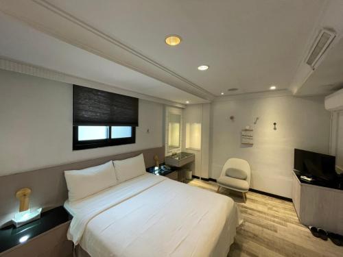 台北桃行旅的卧室配有一张白色大床和一把椅子