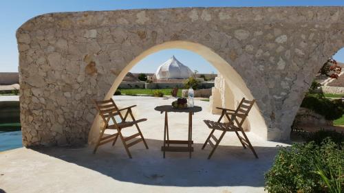 锡瓦Al Nyhaya的一个带桌子和两把椅子的拱门和一个清真寺