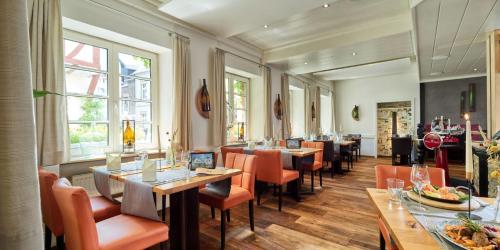 策尔廷根-拉蒂希Hotel Zeltinger-Hof - Gasthaus des Rieslings的配有木桌和橙色椅子的餐厅