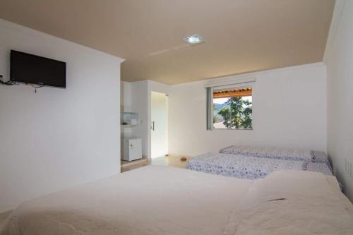 里奥迪孔塔斯Pouso da Soraya的白色的卧室设有一张大床和一个窗户