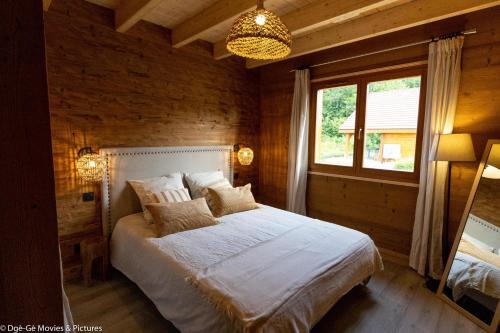 BonlieuLes Jardins du Hérisson Chalet 2的一间卧室设有一张床、一个窗户和一个吊灯。
