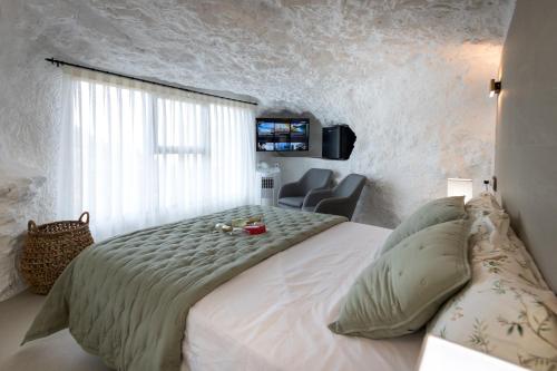 阿尔卡拉德尔胡卡尔Casa túnel Nido de Águilas的卧室配有一张白色大床和一把椅子