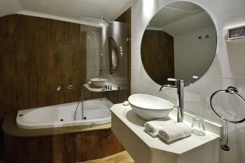 萨法德Romano Hotel Boutique的一间带水槽、浴缸和镜子的浴室
