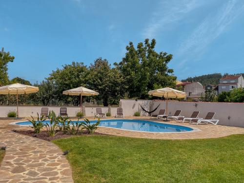 卡尔达斯·德·雷斯Villa Galicia的庭院内一个带椅子和遮阳伞的游泳池