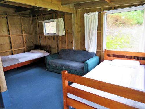Matauri BayMatauri Bay Holiday Park的客房设有两张床、一把椅子和窗户。