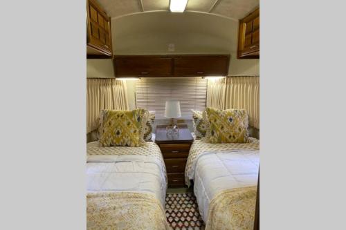 博福特Beautiful Airstream, Beaufort SC-Enjoy the Journey的一间卧室配有两张床和一张带台灯的桌子
