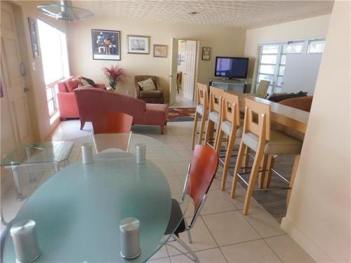 劳德代尔堡Dolphin Isles Resort的用餐室以及带玻璃桌和椅子的客厅