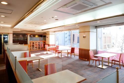 佐世保瑞索尔佐世保酒店的餐厅设有桌椅和大窗户。