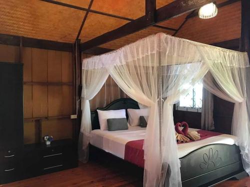 俊穆岛Kohjum Seafront Resort的卧室配有带白色窗帘的天蓬床
