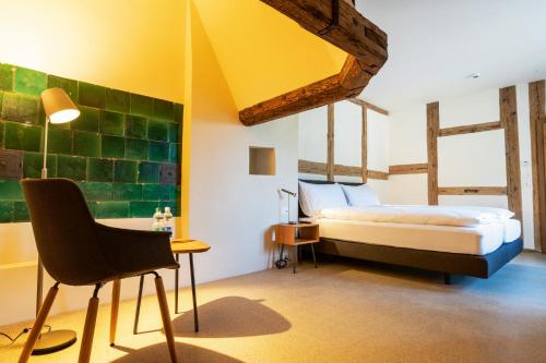 SchlossruedResort Schloss Rued的卧室配有1张床、1张桌子和1把椅子