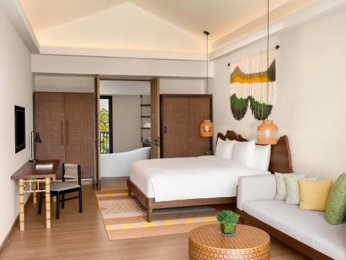 富国New World Phu Quoc Resort的一间卧室配有一张床、一张桌子和一张沙发