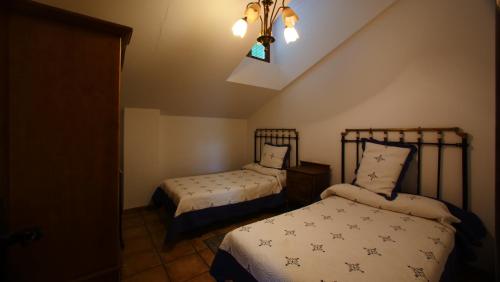 SaldañaCasa Rural Plaza Vieja Saldaña的一间卧室设有两张床、一个窗户和一个吊灯。