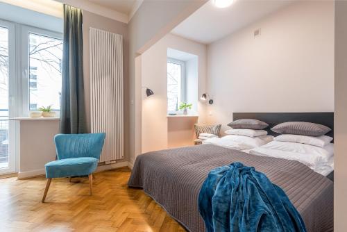 华沙Plater & Poznanska Serviced Apartments的一间卧室配有一张大床和一张蓝色椅子